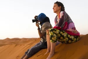 two-people-sitting-top-dune-taking-photos-min